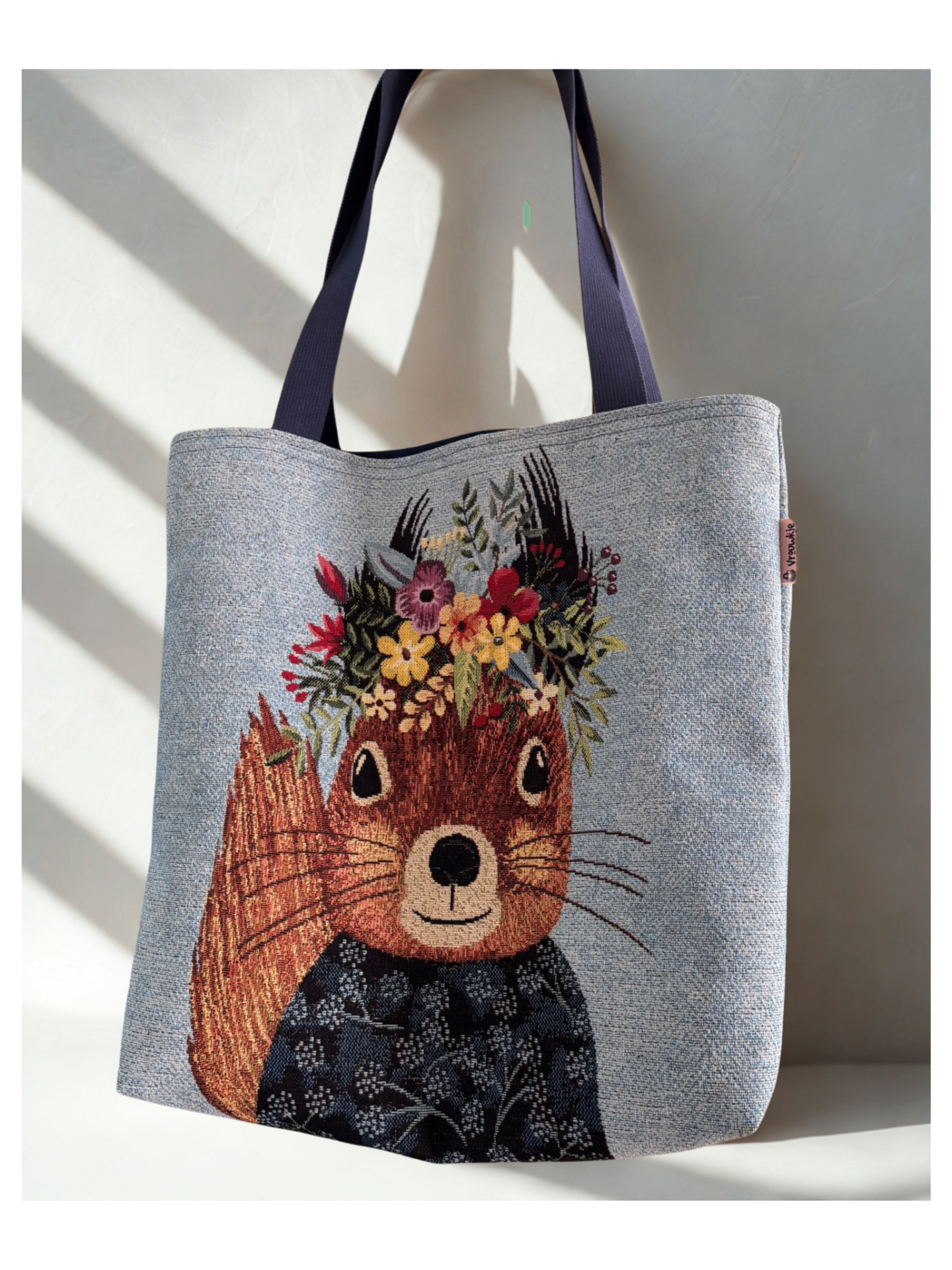 Handgemaakte tote tas met bloemmotief en marine middenband op warm-zandkleurige achtergrond